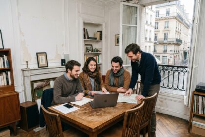 Groupe de quatre adultes discutant de papiers dans un appartement parisien