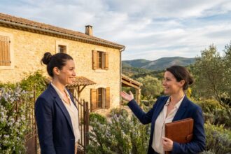 Agent immobilier d'ARE Immo devant une maison en pierre typique de Saint-Martin-de-Londres dans l'Hérault